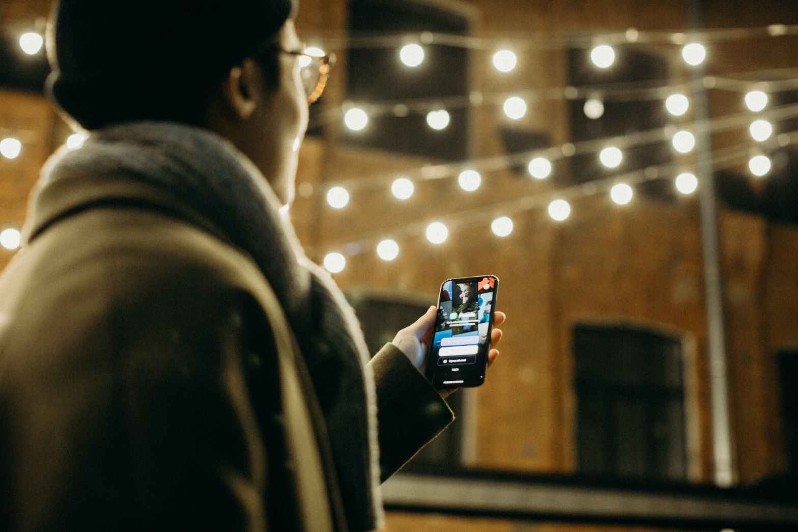 selective focus photography of man using smartphone beside string lights for article about user experience, UX, and content writing