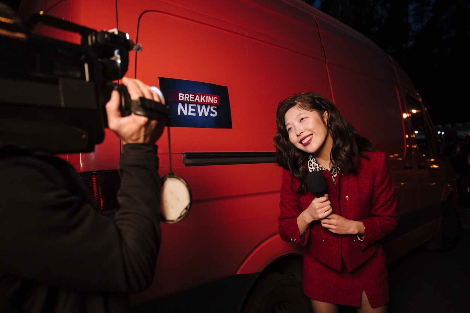 a reporter holding a microphone near a red van to highlight the benefits of working with a press release agency as described in our latest blog