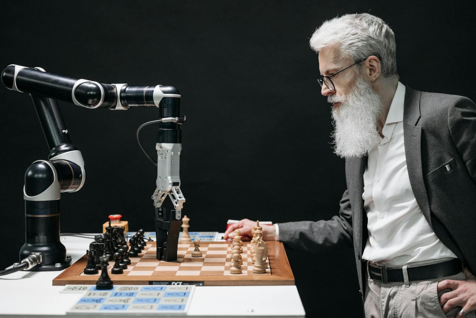 a bearded man playing chess against a robot for an article on ai optimization